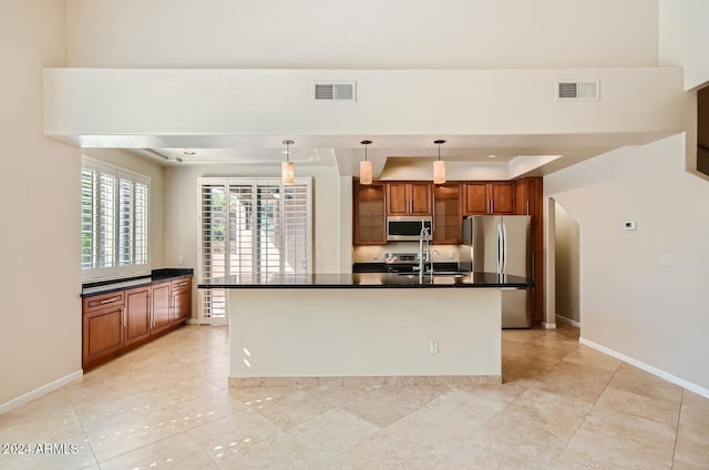 kitchen with light tile patterned floors, pendant lighting, stainless steel appliances, a center island with sink, and sink