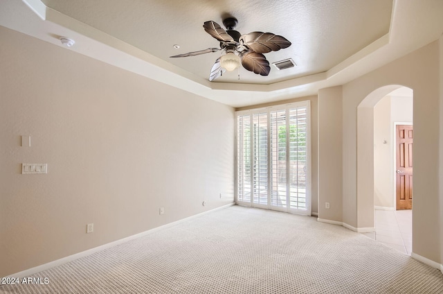 carpeted empty room with ceiling fan, a raised ceiling, and a textured ceiling