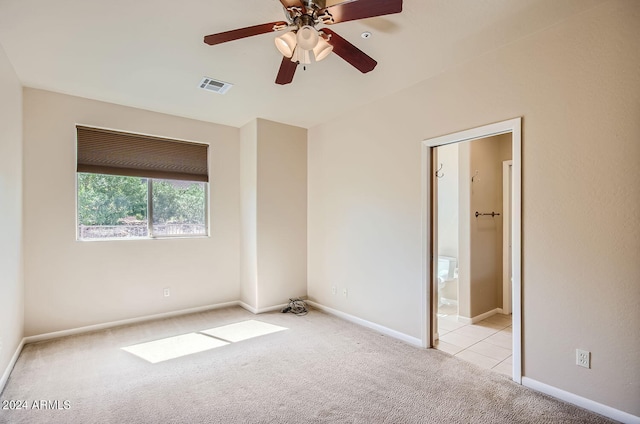 unfurnished bedroom featuring ceiling fan, light colored carpet, and ensuite bath