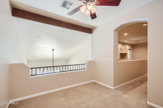 carpeted empty room featuring vaulted ceiling with beams and ceiling fan