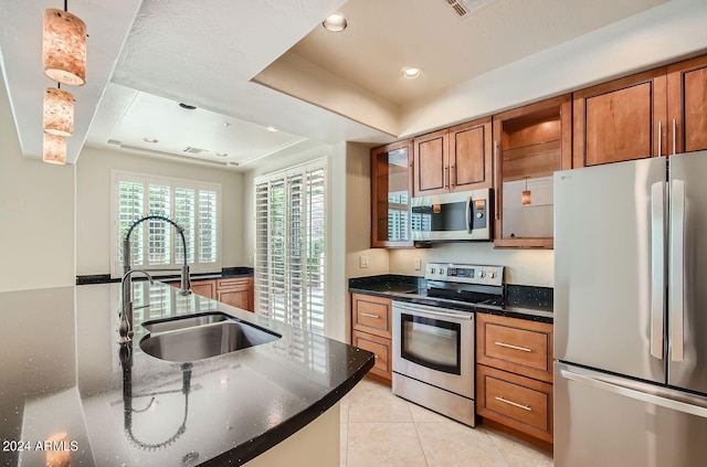 kitchen with appliances with stainless steel finishes, hanging light fixtures, a raised ceiling, light tile patterned floors, and sink