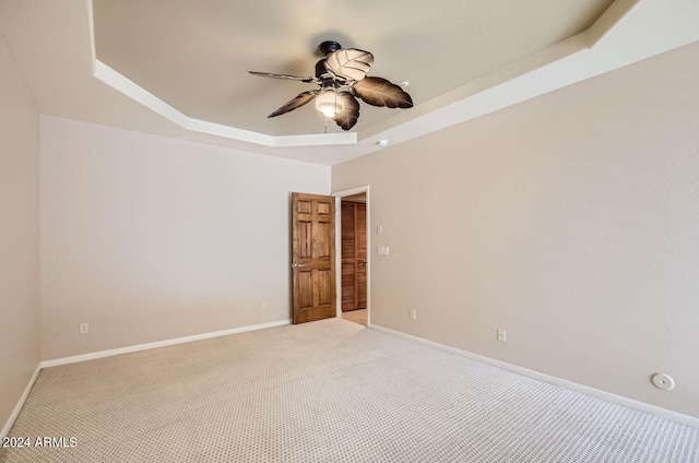 empty room featuring carpet, ceiling fan, and a raised ceiling