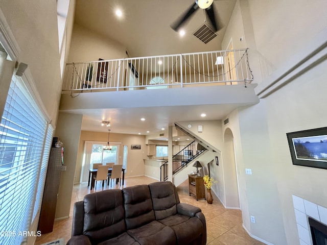 living room featuring stairway, light tile patterned floors, a ceiling fan, baseboards, and a high ceiling