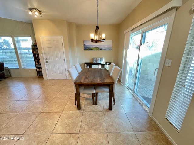 dining area with an inviting chandelier, light tile patterned floors, and baseboards