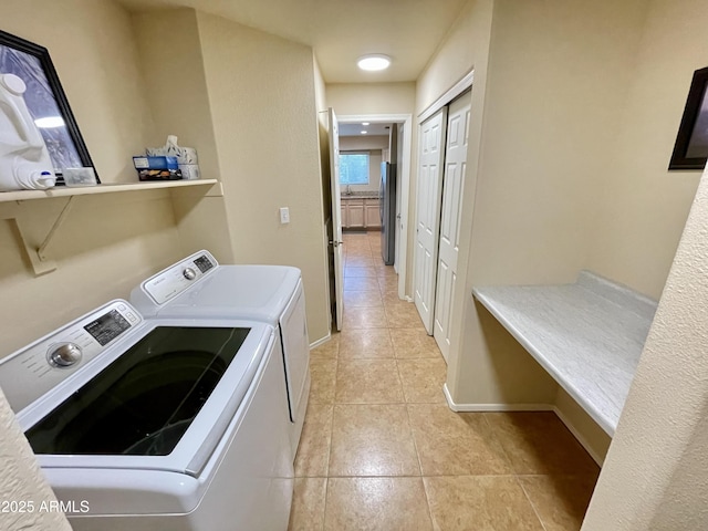 laundry room featuring washer and clothes dryer, laundry area, baseboards, and light tile patterned floors