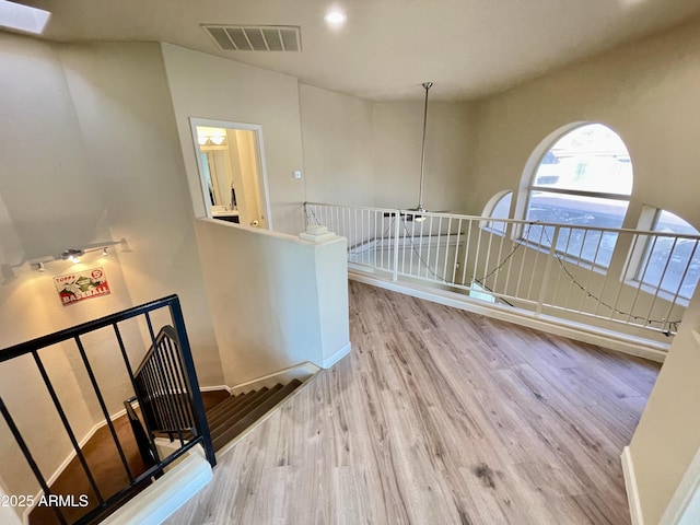 interior space with wood finished floors, an upstairs landing, visible vents, and baseboards