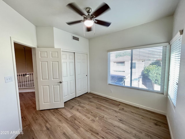 unfurnished bedroom with visible vents, ceiling fan, baseboards, wood finished floors, and a closet