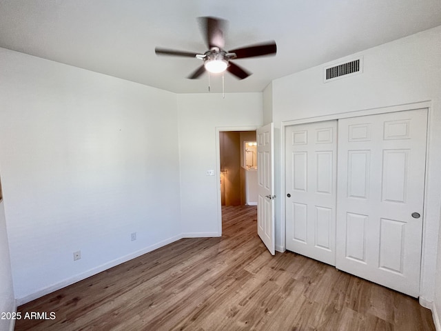 unfurnished bedroom with a ceiling fan, wood finished floors, visible vents, baseboards, and a closet