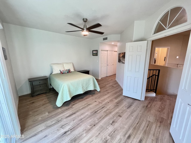 bedroom with light wood finished floors, visible vents, vaulted ceiling, a closet, and a ceiling fan