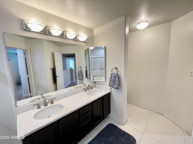 bathroom featuring a sink, baseboards, double vanity, and tile patterned floors