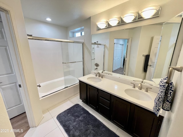 bathroom with a sink, combined bath / shower with glass door, double vanity, and tile patterned floors