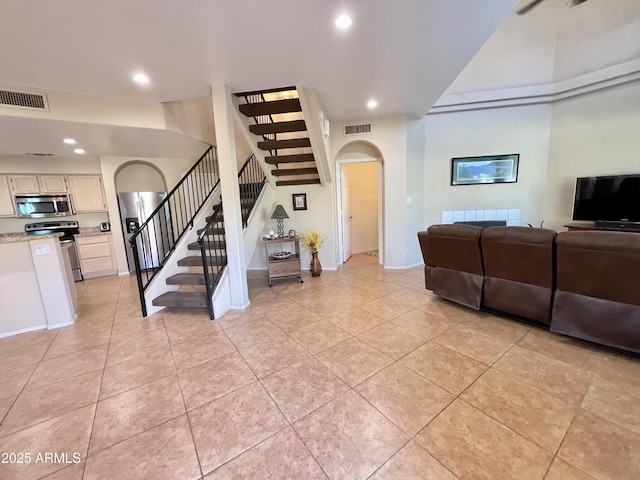 living room with arched walkways, visible vents, recessed lighting, and stairs