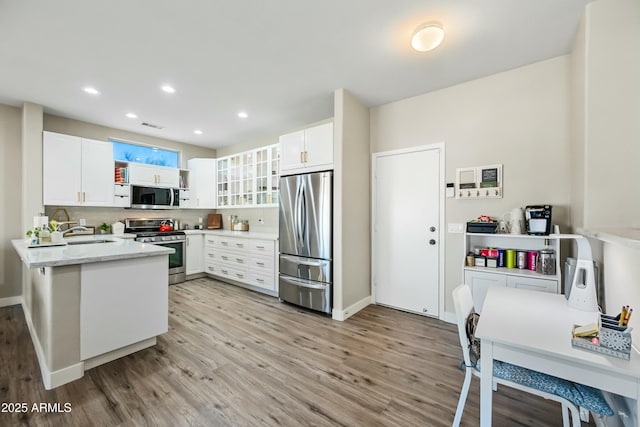 kitchen featuring sink, white cabinetry, light hardwood / wood-style flooring, appliances with stainless steel finishes, and decorative backsplash