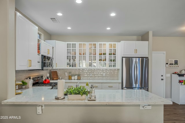 kitchen with white cabinetry, stainless steel appliances, kitchen peninsula, and light stone countertops