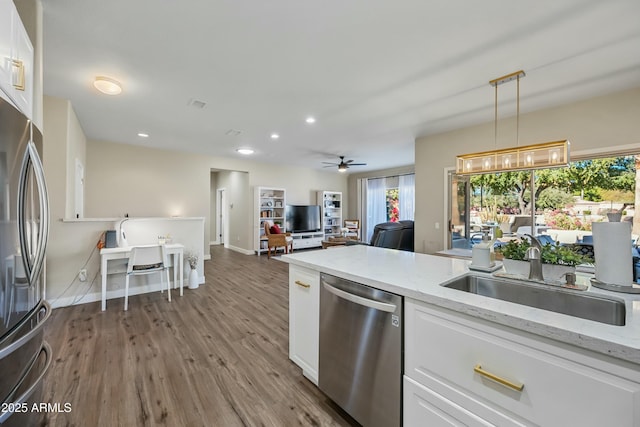 kitchen featuring decorative light fixtures, sink, white cabinets, stainless steel appliances, and light stone countertops