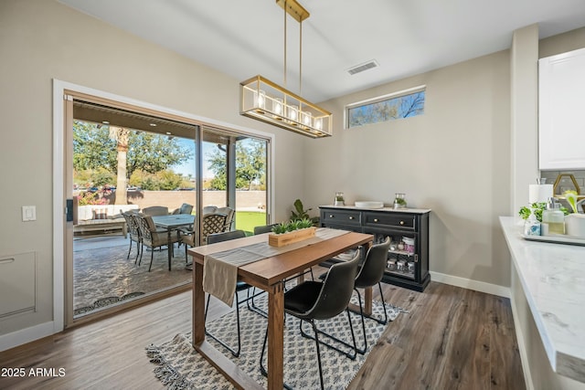 dining area with dark hardwood / wood-style floors and a notable chandelier