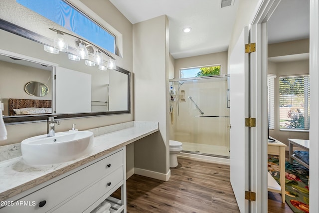 bathroom with hardwood / wood-style flooring, toilet, vanity, and a shower with shower door