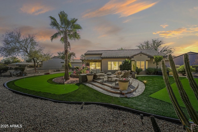 back house at dusk featuring a patio and an outdoor hangout area