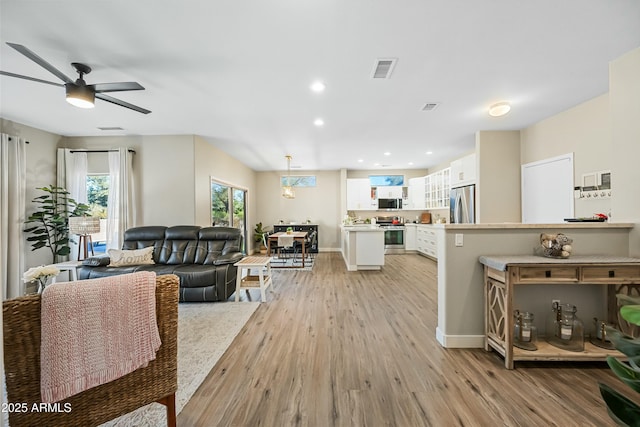 living room with ceiling fan and light wood-type flooring