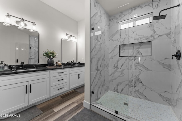 bathroom with tiled shower, hardwood / wood-style floors, and vanity