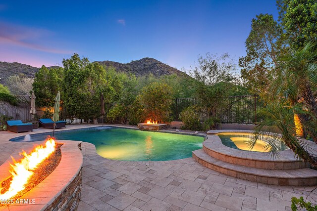 26036 N 85th Dr, Peoria, AZ 85383 - pool at dusk with a fire pit, a mountain view, an in-ground hot tub, and a patio area