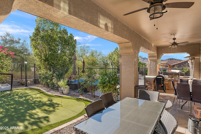26036 N 85th Dr, Peoria, AZ 85383 - fenced backyard with a ceiling fan, area for grilling, an area to practice putting, outdoor dining space, and a patio