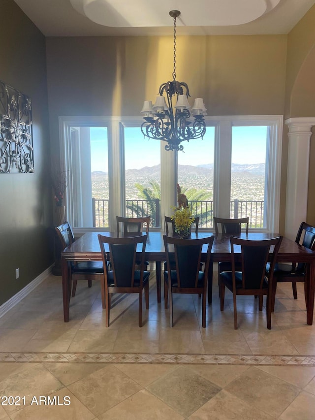 tiled dining space featuring ornate columns and a notable chandelier