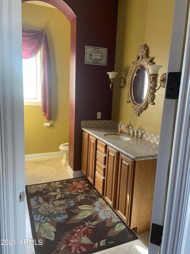 bathroom with toilet, tile flooring, and vanity