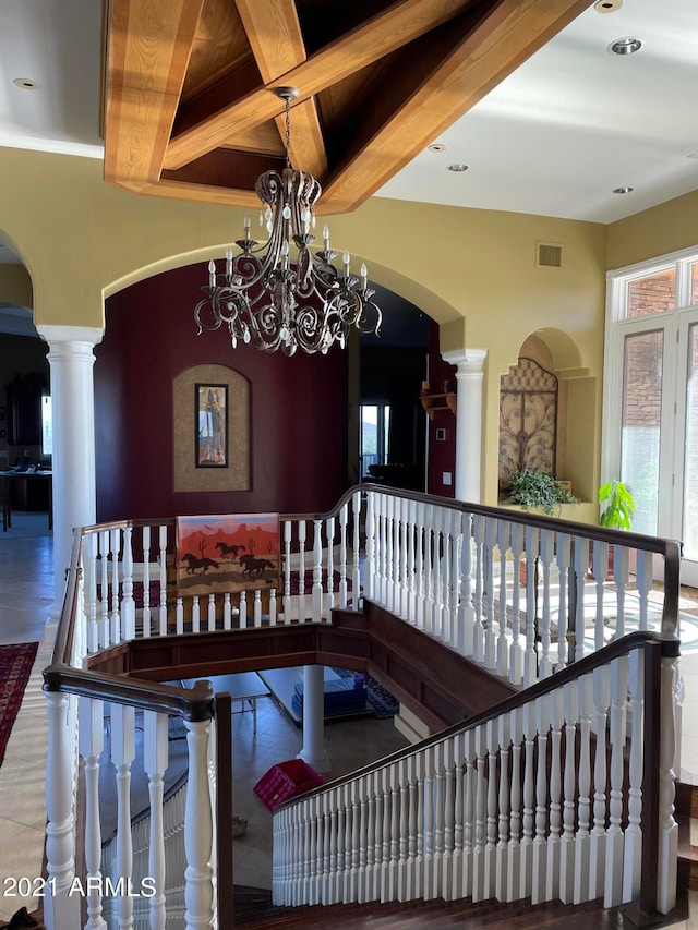 interior space featuring ornate columns, beamed ceiling, and a notable chandelier