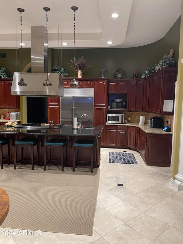 kitchen featuring backsplash, pendant lighting, a tray ceiling, and built in appliances