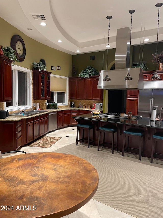 kitchen with hanging light fixtures, a tray ceiling, stainless steel appliances, sink, and light tile floors