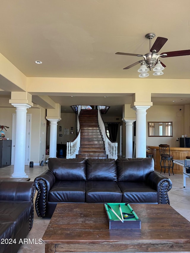 tiled living room with ceiling fan and ornate columns