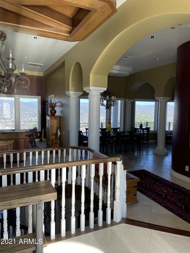 corridor featuring tile flooring, a chandelier, and ornate columns