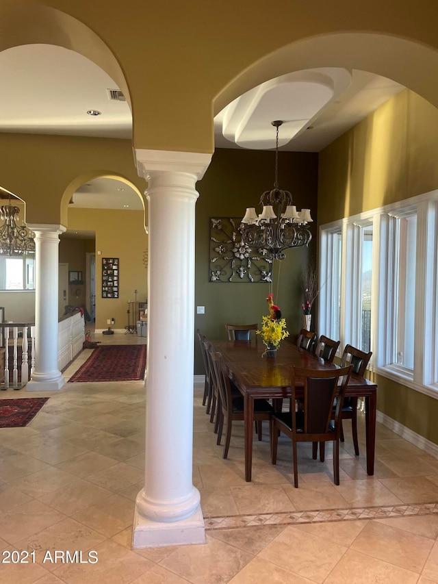 dining area featuring decorative columns, a notable chandelier, and light tile flooring