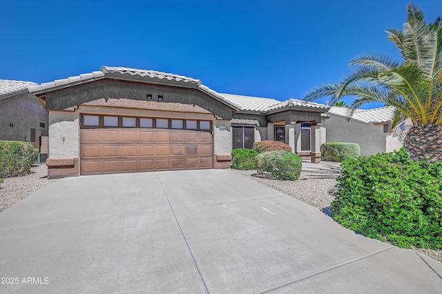 view of front of house with stucco siding, an attached garage, driveway, and a tile roof