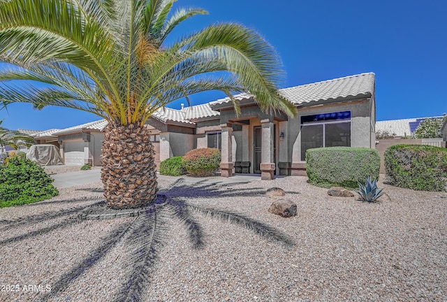 view of front of property featuring a garage, a tiled roof, and stucco siding