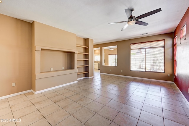 interior space with baseboards, built in features, visible vents, ceiling fan, and light tile patterned floors