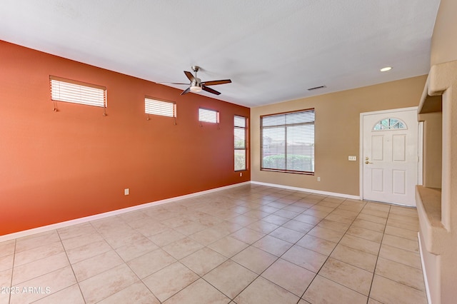 empty room with ceiling fan, baseboards, visible vents, and light tile patterned floors