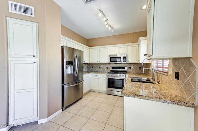 kitchen featuring backsplash, visible vents, light tile patterned flooring, light stone countertops, and appliances with stainless steel finishes