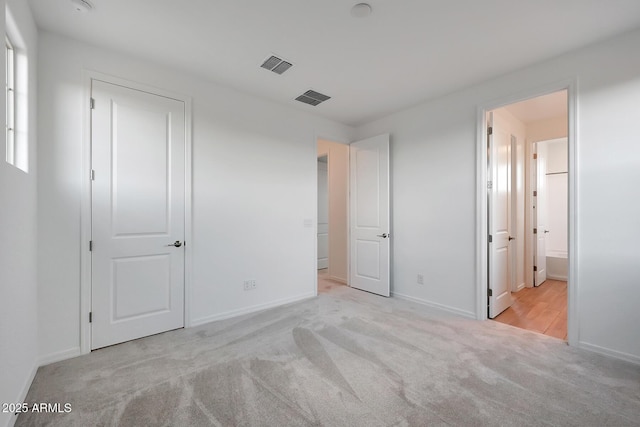 unfurnished bedroom featuring connected bathroom and light carpet