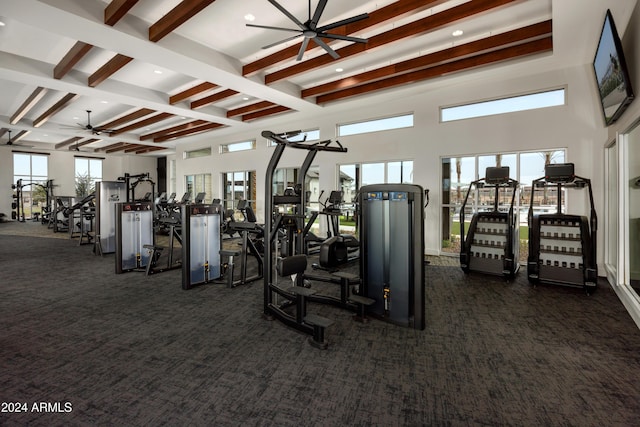 exercise room featuring coffered ceiling, a wealth of natural light, and dark carpet