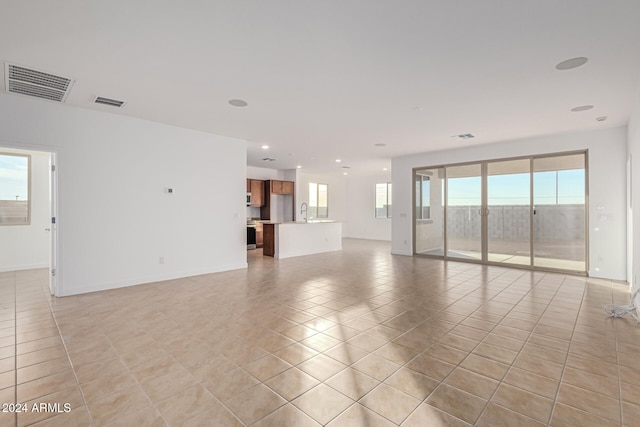 empty room featuring a healthy amount of sunlight, light tile patterned floors, and sink