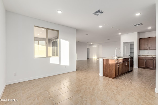 kitchen featuring stainless steel dishwasher, dark brown cabinetry, sink, light tile patterned floors, and an island with sink