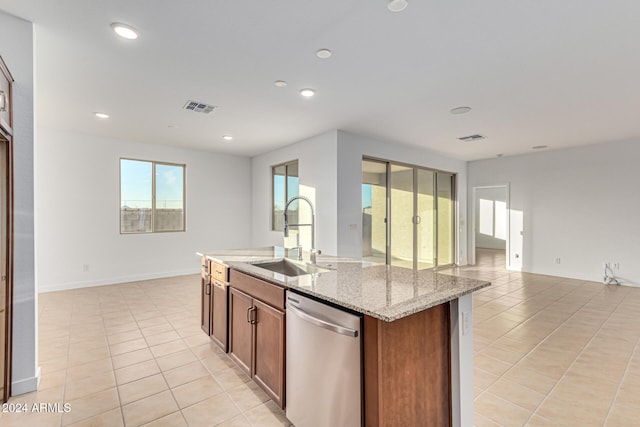 kitchen with a kitchen island with sink, sink, stainless steel dishwasher, light stone countertops, and light tile patterned floors