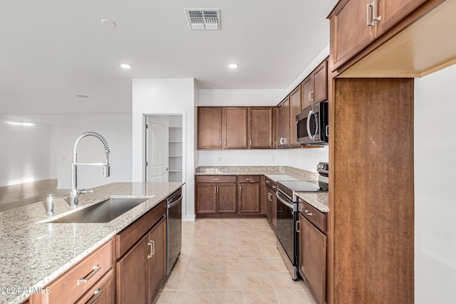 kitchen featuring light stone counters, sink, light tile patterned floors, and appliances with stainless steel finishes