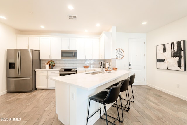 2511 W Queen Creek Rd Unit 325, Chandler, AZ 85248 - kitchen featuring stainless steel appliances, light wood-type flooring, a kitchen breakfast bar, white cabinetry, and recessed lighting