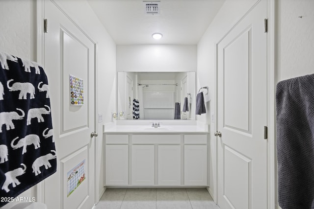 bathroom featuring tile patterned flooring, vanity, and walk in shower