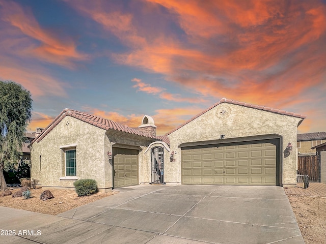 mediterranean / spanish-style home with a garage, a tiled roof, and stucco siding