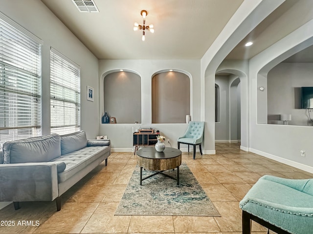 living area featuring a chandelier, tile patterned flooring, visible vents, and baseboards