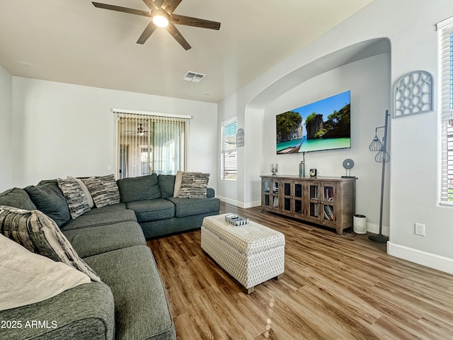 living area with baseboards, ceiling fan, visible vents, and wood finished floors